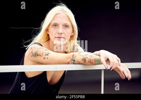 Junge Frau mit blondem Haar, die sich hinlehnt und wegschaut Geländer Stockfoto