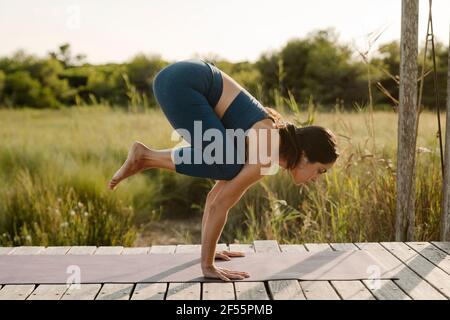 Frau mit mittlerem Erwachsenenalter, die im Pavillon Yoga-Haltung im Handstand macht Stockfoto