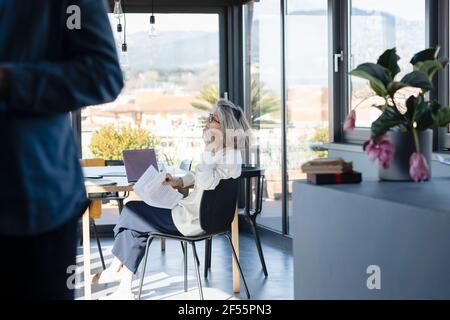Mann, der mit einer nachdenklichen Frau im Hintergrund zu Hause steht Stockfoto