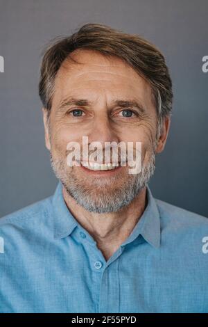 Lächelnder Mann mit Bart vor grauem Hintergrund Stockfoto