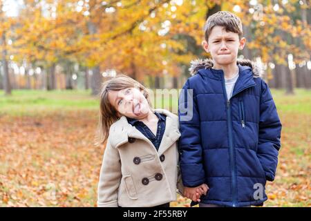 Geschwister tragen eine Jacke und halten die Hände im Wald Stockfoto