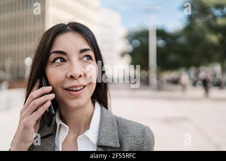 Erwägen einer Geschäftsfrau, die in der Stadt auf einem Smartphone spricht Stockfoto