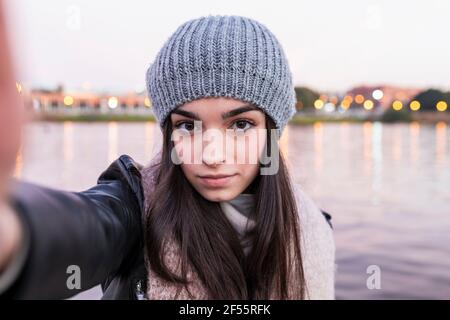 Teenager-Mädchen, das während des Sonnenuntergangs Selfie gegen den Fluss nimmt Stockfoto