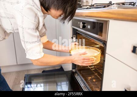 Frau, die einen Käsekuchen in den Ofen legte Stockfoto