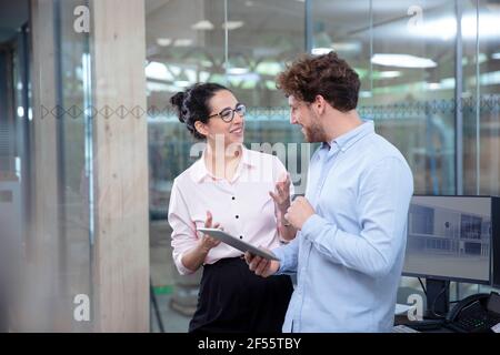 Lächelnde Unternehmer und Unternehmerinnen diskutieren im Büro Stockfoto