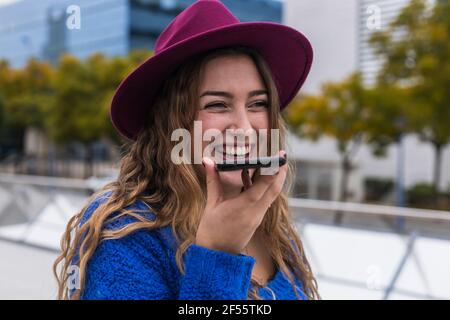 Fröhliche Frau, die lachte, als sie Voicemail über das Mobiltelefon schickte Stockfoto