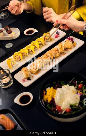 Junge Freundinnen, die Sushi mit Essstäbchen im Restaurant essen Stockfoto