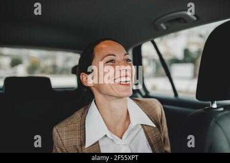 Fröhliche weibliche Profikinderin, die auf dem Rücksitz sitzt, während sie einreist Taxi Stockfoto