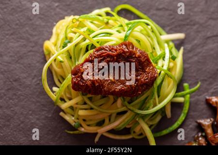 Zucchini-Spaghetti mit getrockneten und getrockneten Tomaten Stockfoto