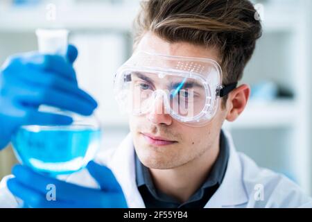 Schöner männlicher Wissenschaftler, der Chemikalien im Labor untersucht Stockfoto