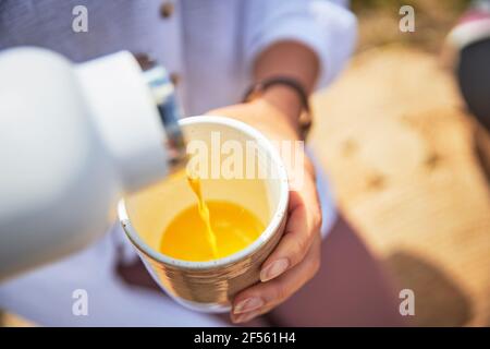 Hände einer Frau, die Orangensaft in Glas gießt Stockfoto