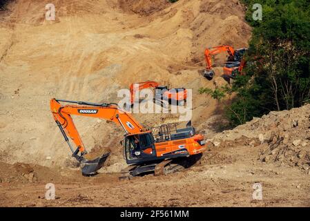 Bulgarien, Radanovo, 19th. MAI 2020: Drei orangefarbene Kettenbagger, die während des Baus der South Stream-Pipeline in Bulgarien an einem Hang graben Stockfoto