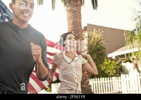 Glücklicher Mann und Frau, die mit amerikanischer Flagge laufen Stockfoto