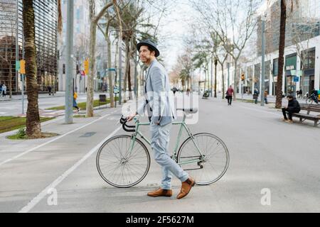 Männlicher Unternehmer zu Fuß mit dem Fahrrad auf der Straße in der Stadt Stockfoto