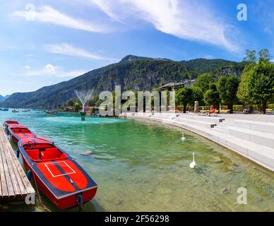 Österreich, Salzburg, Sankt Gilgen, Motorboote liegen im Sommer am Ufer des Wolfgangsees mit Promenade und Zwolferhorn im Hintergrund Stockfoto