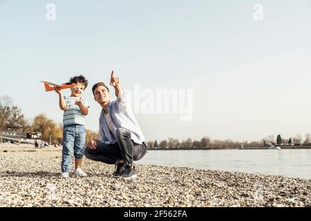 Vater gestikulierte beim hocken von Sohn stehend mit Spielzeug auf Sonniger Tag Stockfoto