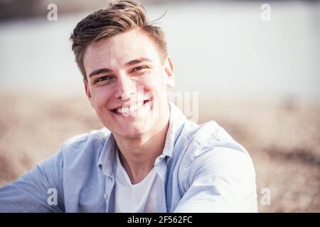 Schöner junger Mann, der an einem sonnigen Tag lächelt Stockfoto