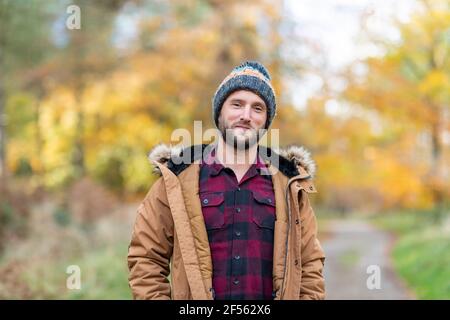 Lächelnder Mann mit Strickmütze starrte auf den Wald Stockfoto