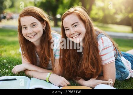 Ginger Zwillingsmädchen verbringen ihre Sommerschulpause, um sich auf die Hochschulprüfungen vorzubereiten. Zukünftiger Arzt und Rechtsanwalt, der Spaß hat, an einem sonnigen Tag zu lächeln Stockfoto