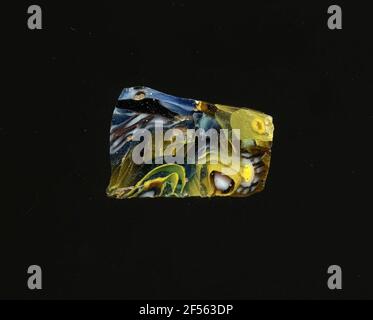 Fragment eines Gefäßes. Eine niedrige Krümmung des Glassfragmentes ermöglicht die Zuordnung zu einem Gefäß. Das violette Glas ist mit zwei Arten von Blumen in millefiori-Technologie und Streifen in verschiedenen Farben dekoriert. Die Blüten sind entweder aus einem weißen Kern mit einer transparenten Kontur auf einer gelben Spirale auf einem blauen Hintergrund zu verbreiten, oder von einem gelben Punkt mit weißer Kontur, um die weißen Punkte die Blütenblätter zu spezifizieren. Für die Herstellung von verschiedenfarbigen Gläsern zu Röhren und Stäben geformt. Diese wurden komprimiert und erhitzt, was zu einem langen Balken führte. Die Glasscheiben ​​now hatten verschiedene amorphe oder florale patte Stockfoto