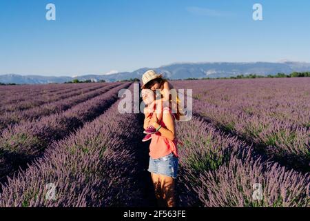 Mutter Huckepack kleine Tochter in riesigen Sommer Lavendel Feld Stockfoto