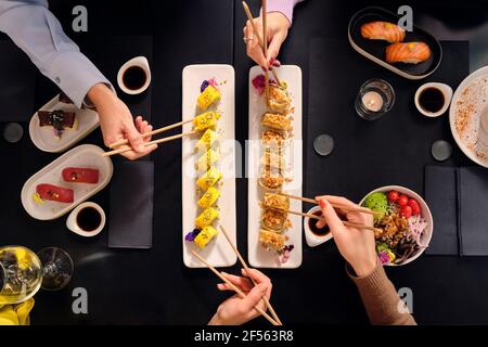 Weibliche Gäste essen frisches Sushi mit Essstäbchen im Restaurant Stockfoto