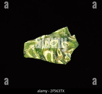 Zwei Mosaikglasfragmente. Die beiden zugehörigen grünen Glasfragmente bestehen aus mehreren weißen Kreisen mit grüner Mitte und hellgrüner Umrandung. An diesen Stücken ist die Fertigungstechnik gut erkennbar: Es handelt sich um einen Abschnitt durch einen Stab aus mehreren gewellten Glasröhren (von innen nach außen dunkelgrün, weiß, hellgrün) in dunkelgrünem Glas.in der Römerzeit verwendete es farbiges, ornamentes Glas für Gefäße, Mosaike, Wanddekorationen und Möbelschmuck. Für die Herstellung wurden verschiedenfarbige Gläser zu Rohren und Stäben geformt. Diese wurden komprimiert und erhitzt, was zu einem langen Balken führte. Das gl Stockfoto