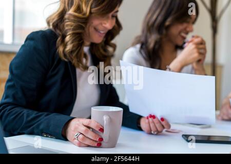 Weibliche Mitarbeiter, die Kaffee trinken, während sie im Büro planen Stockfoto