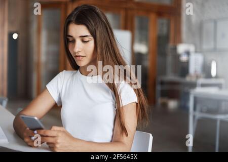 Junge Frau sucht Arbeit mit Online-Diensten auf ihrem Handy. Junge Fachkräfte sind nach der Universität gefragt. Stockfoto