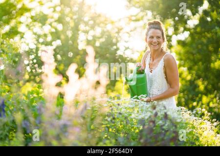 Porträt einer jungen Frau, die im Garten des Frühlings Blumen gießt Stockfoto