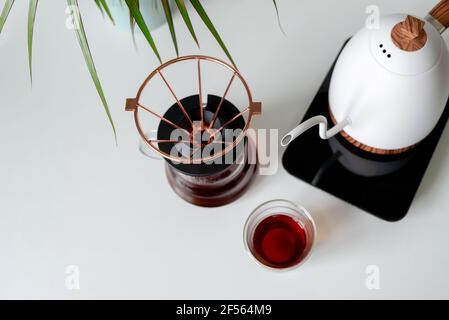 Gebrauter, gemahlener Kaffee in einer Tropfmethode, auf einem weißen Tisch. Manuelles Füllen des Kaffees. Speicherplatz kopieren. Stockfoto