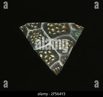 Fragment eines Gefäßes. Eine niedrige Krümmung des Glassfragmentes ermöglicht die Zuordnung zu einem Gefäß. Das dunkelbraune Glas wird von einem Gitter aus weißen Linien durchzogen, die an Bienenwaben erinnern. In den Feldern gibt es Blumen in millefiori-Technologie, die aus runden gelben Punkten bestehen. Für die Herstellung wurden verschiedenfarbige Gläser zu Rohren und Stäben gebildet. Diese wurden komprimiert und erhitzt, was zu einem langen Balken führte. Die Glasscheiben hatten verschiedene amorphe oder florale Muster. ​​now Danach wurden mehrere dieser Blutplättchen verschmolzen, wieder erhitzt und geformt. Burry für den aufwendigen Herstellungsprozess Stockfoto
