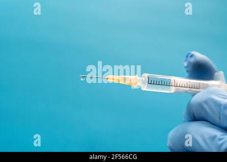 Hand der Person, die einen Schutzhandschuh mit einer Spritze trägt Stockfoto
