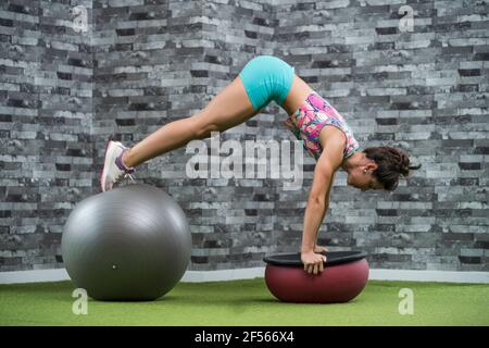 Aktive Sportlerin, die im Fitnessstudio mit Fitnessball trainiert Stockfoto