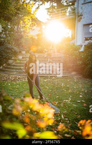 Frau fegende mit Besen im Garten an sonnigen Tag Stockfoto