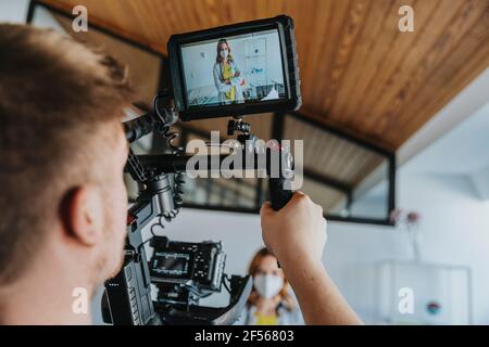 Kameramann filmt einen Arzt mit einer schützenden Gesichtsmaske, an der er steht Klinik Stockfoto