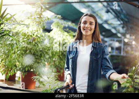 Junge Gärtnerin sammelt Pflanzen zum Verkauf in ihrem eigenen Gewächshaus Online-Shop. Stockfoto