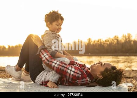 Verspielte Mutter und Sohn schauen sich am See an Bei Sonnenuntergang Stockfoto