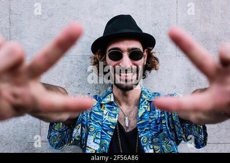 Glücklicher Mann mit hawaiianischem Hemd und Friedensschild vor dem Hotel Der Wand Stockfoto