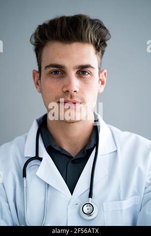 Schöner männlicher Arzt gegen graue Wand im Krankenhaus Stockfoto