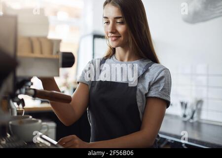 Studentin auf ihrem Sommerjob serviert Kaffee arbeiten als Ein Barista in einer lokalen Konditorei Stockfoto