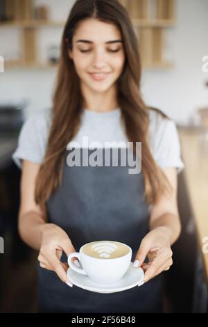 Nahaufnahme des perfekten Latte Art Cappuccino, serviert von einer jungen, aber erfahrenen Barista. Stockfoto