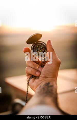 Die Hand des jungen Mannes hält den Navigationskompass Stockfoto