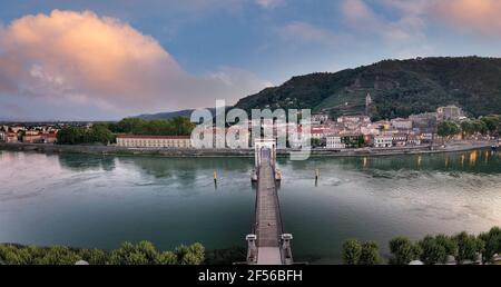 Frankreich, Ardeche, Tournon-sur-Rhone, Panorama der Passerelle Marc Seguin Brücke und Stadt am Flussufer in der Abenddämmerung Stockfoto