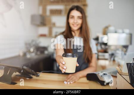 Nahaufnahme des Barista, der einem Gast Kaffee zum Bechern serviert. Stockfoto