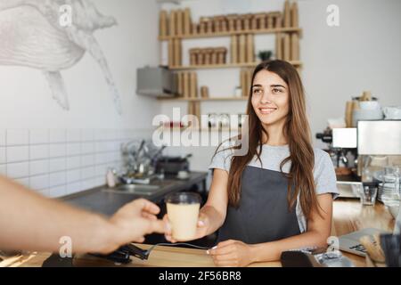Junge Barista serviert Kaffee zu ihrem ersten Kunden gehen heute glücklich aussehen. Stockfoto
