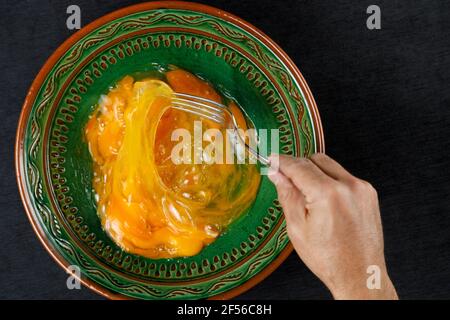 Hand des Mannes, der Eigelb in einer grünen Schüssel mischt Stockfoto