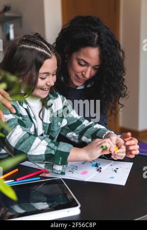 Lächelndes Mädchen, das Bleistift schärft, während es am Tisch im Leben studiert Zimmer Stockfoto