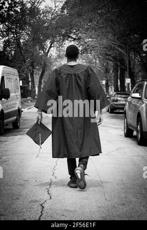 CHICAGO, IL. USA 20. MAI 2020: AUF DEM HÖHEPUNKT DES COVID-19 SPAZIERT EIN JUNGER AFROAMERIKANISCHER ABSOLVENT DURCH DIE STRASSE IN DER WEST PULLMAN-GEGEND Stockfoto