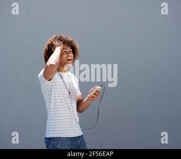 Porträt eines jungen Mannes lächelnd mit Ohrhörern und Handy Stockfoto